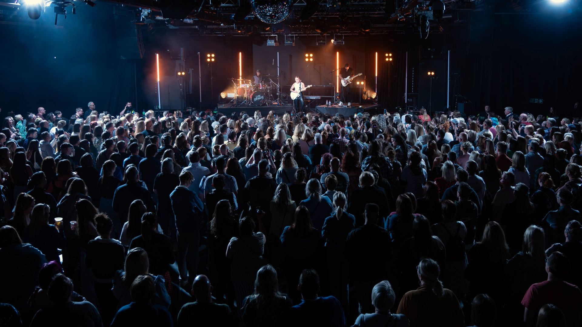 a large crowd of people in front of a stage with lights