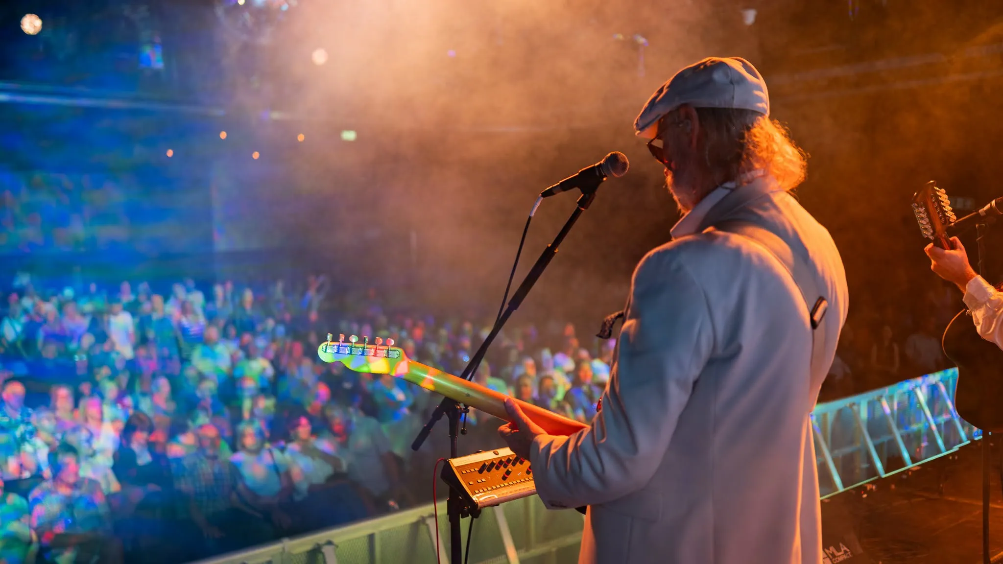 a man playing a guitar on a stage with a crowd watching