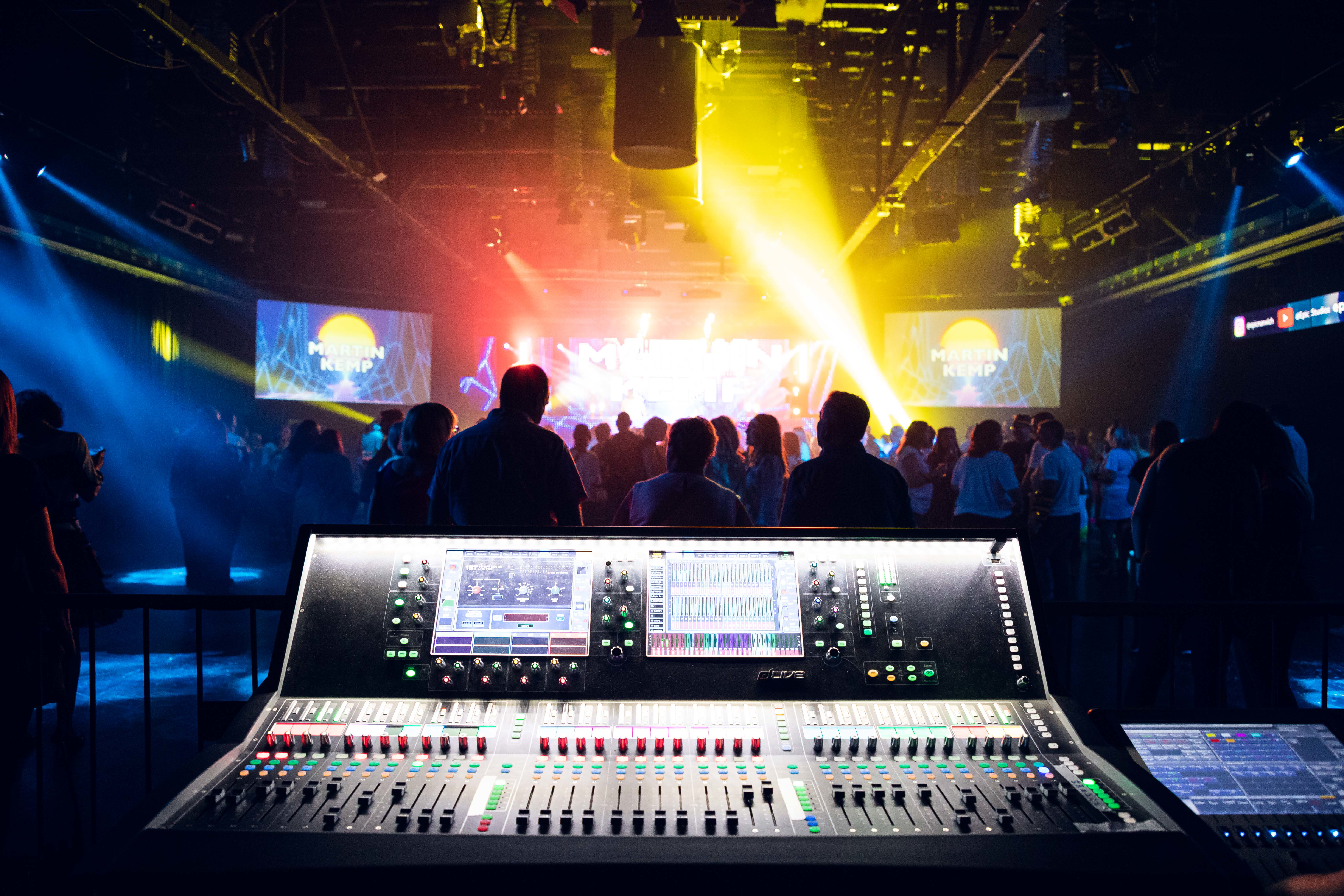 a group of people in a room with a stage and a large screen